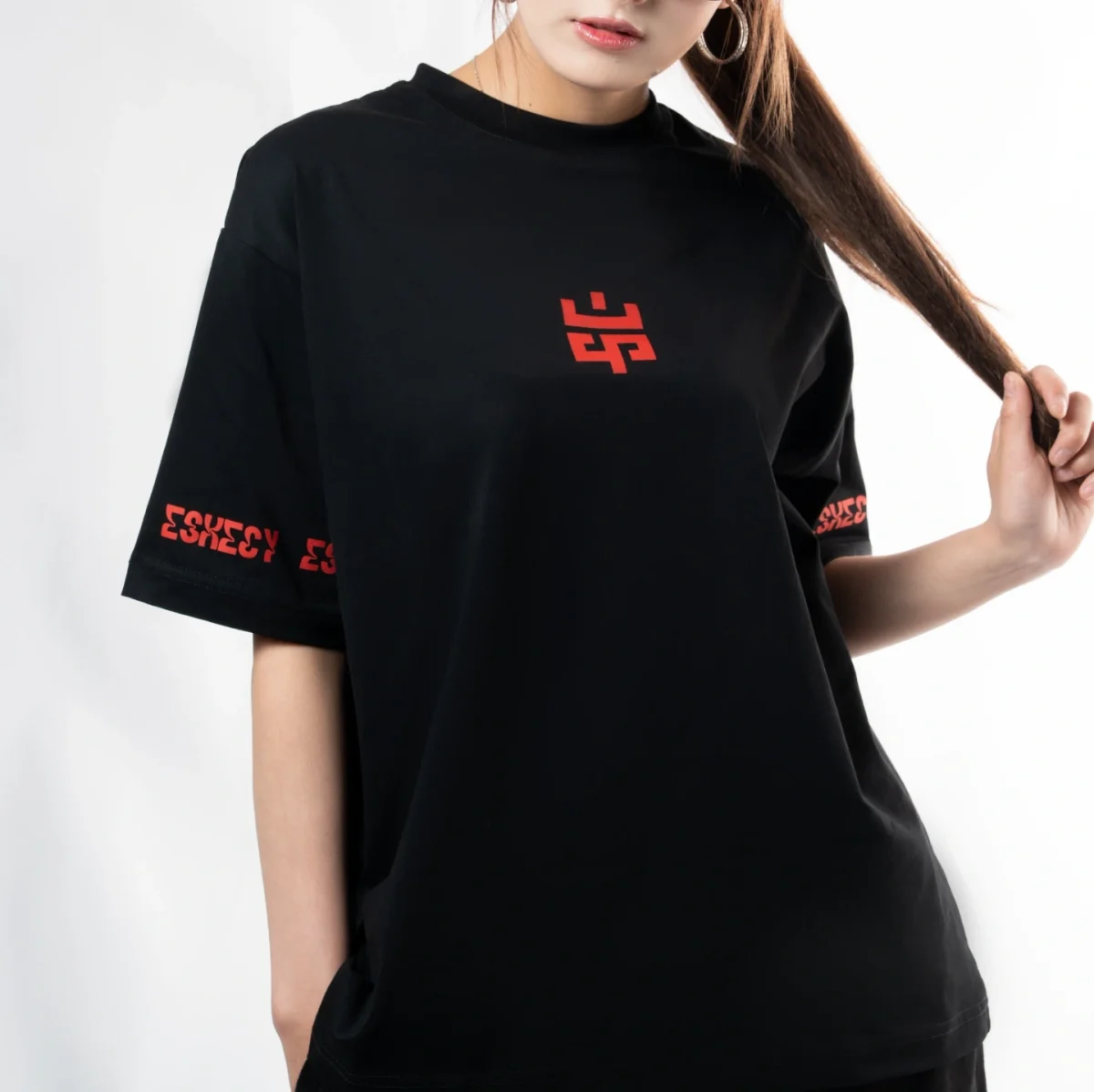 Model wearing the Eskecy Ember Tee, black t-shirt with red logo print on chest and sleeve